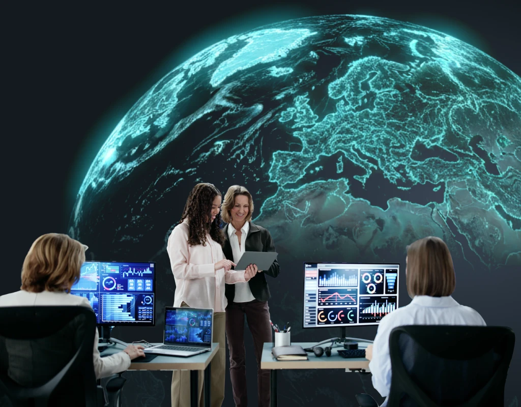  Image showing a team of four people working in an office with glowing monitors, overlaid by a large, glowing digital Earth.